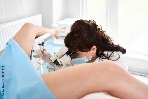 Professional gynecologist examining her female patient on a gynecological chair photo
