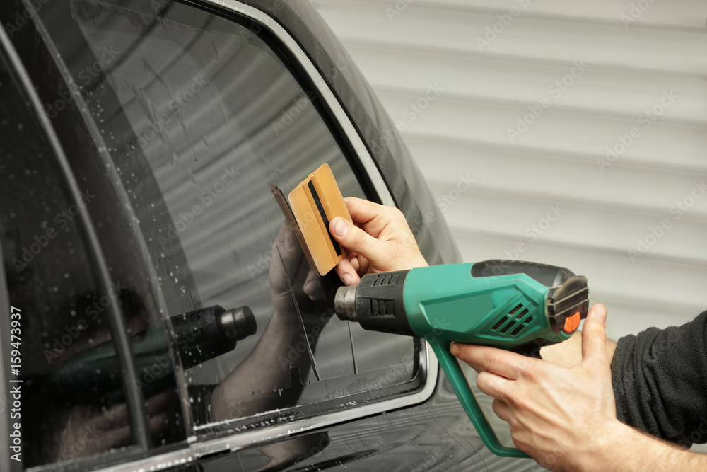Worker applying tinting foil onto car window