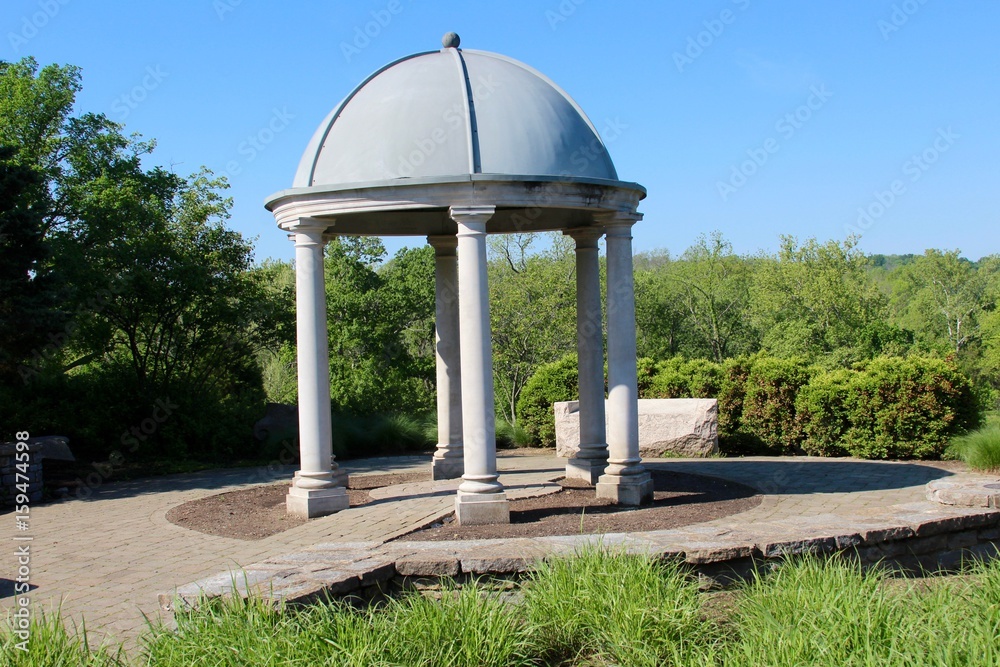 The cement gazebo in the park on a sunny day.