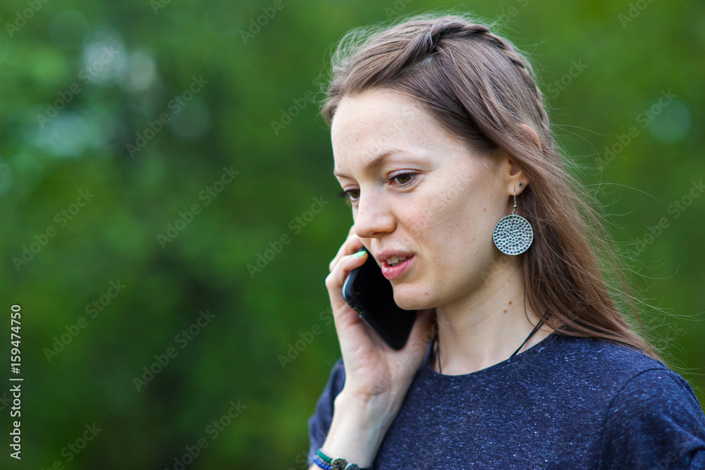 smiling girl speaks by mobile phone against summer green nature. smiling girl speaks by mobile phone against summer green nature.