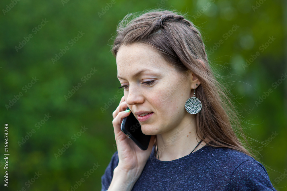 smiling girl speaks by mobile phone against summer green nature. smiling girl speaks by mobile phone against summer green nature.