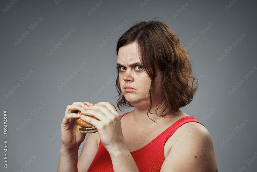 Woman holding a hamburger on a gray background Woman holding a hamburger on a gray background