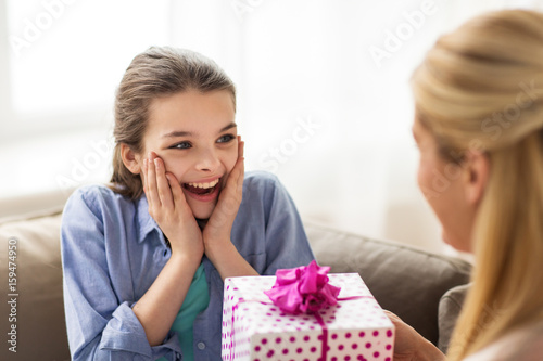 mother giving birthday present to girl at home