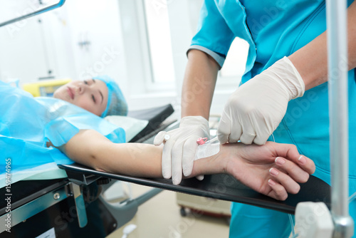 Professional nurse making an injection to a woman lying on operating table at the hospital preparing anesthetic medical healthcare surgery concept.