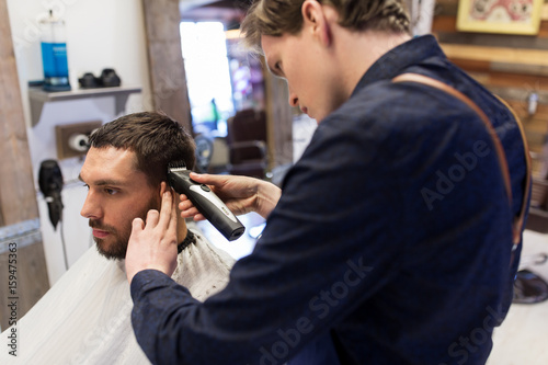 man and barber with trimmer cutting hair at salon
