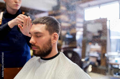 barber applying styling spray to male hair