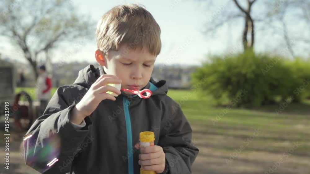 The boy is playing with soap bubbles. A little boy blows bubbles The boy is playing with soap bubbles. A little boy blows bubbles