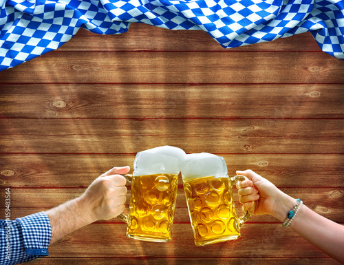 Canvas Print Hands holding up beer mugs under Bavarian flag