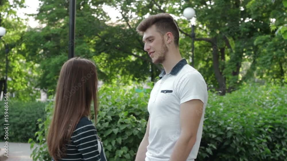 handsome guy smiling and talking with a girl holding her hand in the Park handsome guy smiling and talking with a girl holding her hand in the Park