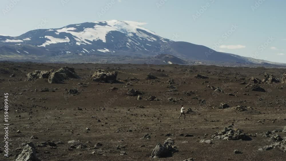 Wide shot of woman running in field near mountain. Rangarvallasysla, Iceland Wide shot of woman running in field near mountain. Rangarvallasysla, Iceland