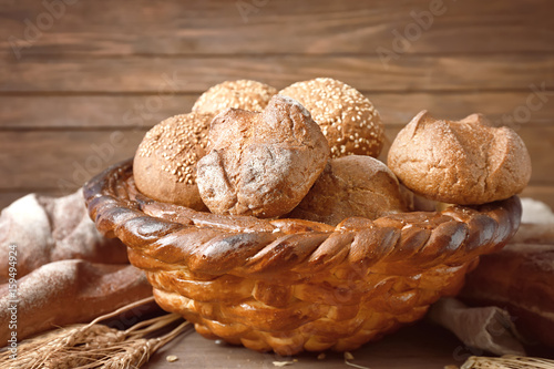 Baked basket with fresh buns on wooden background