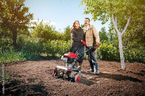 Happy couple of a family of farmers on their garden rejoice on a sunny day after plowing the land