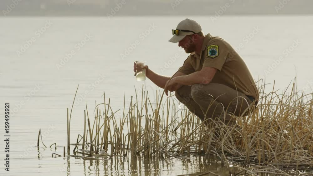 Medium shot of park ranger collecting water sample from lake. Vineyard, Utah, United States
