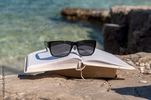 Reading open book at beach near the sea during summer vacation