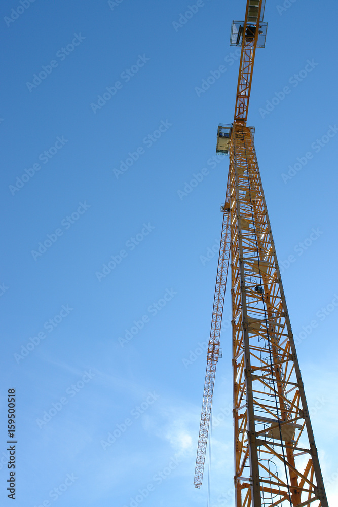 Yellow tower crane against blue sky on construction site. Yellow tower crane against blue sky on construction site.