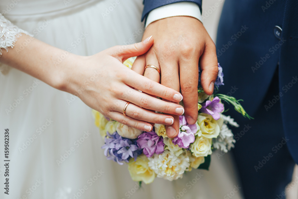 the groom holds the bride holding hands on a wedding bouquet the groom holds the bride holding hands on a wedding bouquet