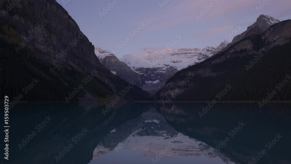 Wide time lapse shot of sunrise over still mountain lake. Lake Louise, Alberta, Canada