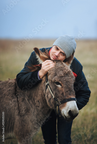 The man hugs the donkey in a friendly way. 