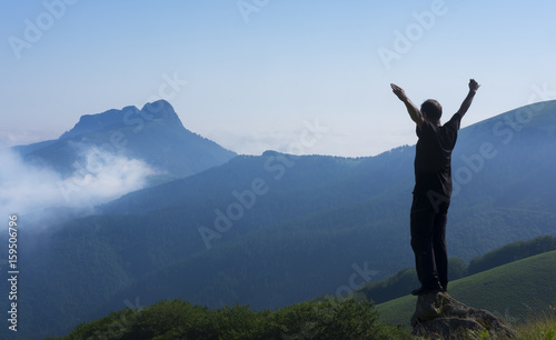 Successful man raising arms while hiking in the mountains