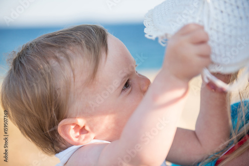 Mother with hat embracing little dougter at beach