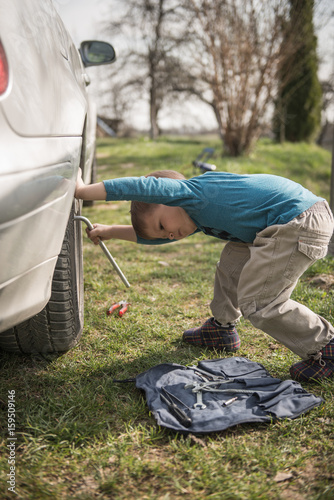 Little boy struggling to fix car tyre