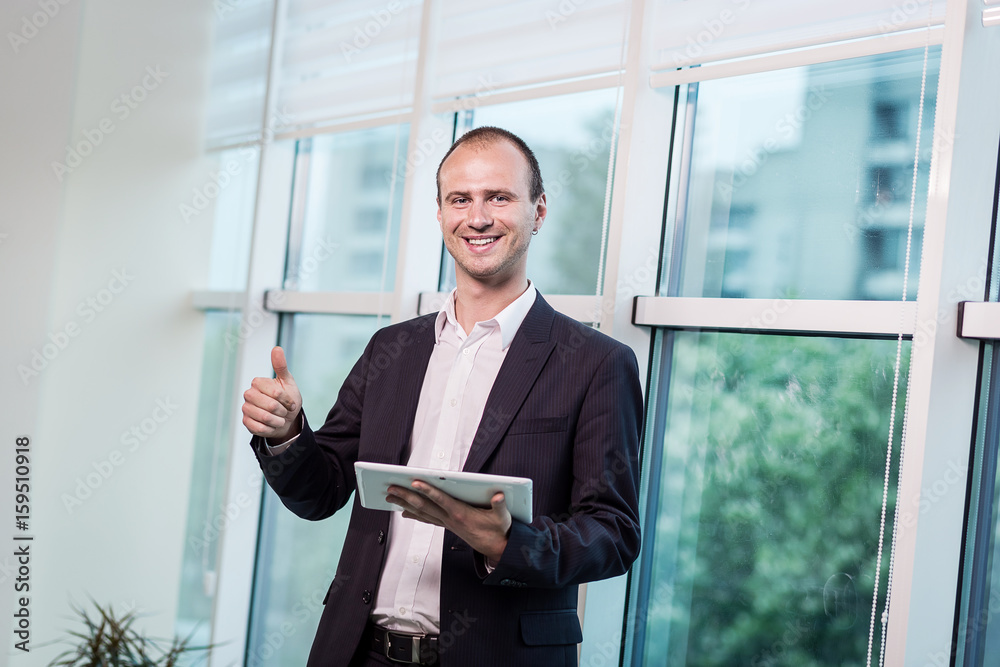 Fototapeta premium Close up image of business man holding a digital tablet,Portrait of handsome young man working with tablet in the office.Intelligent and confidents businessman holding touch pad with infographics