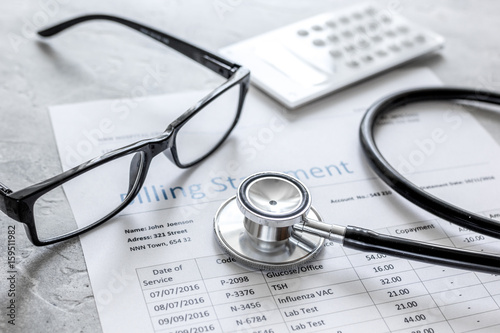 medical treatmant billing statement with stethoscope and glasses on stone background photo
