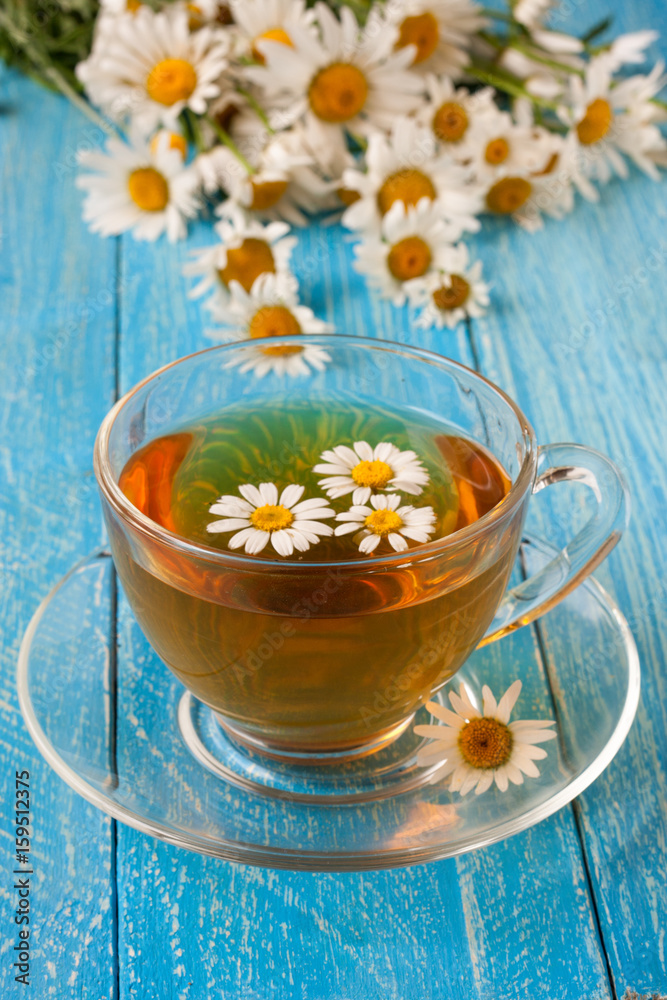 Herbal tea with fresh chamomile flowers on blue wooden background Herbal tea with fresh chamomile flowers on blue wooden background