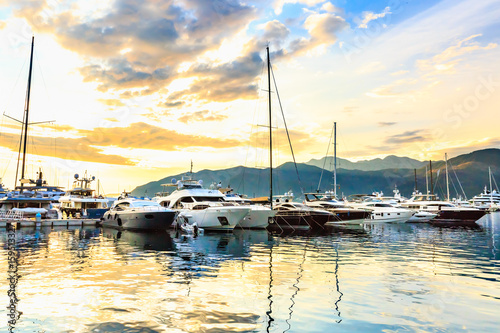 Luxury yachts and sailing boats docked in marina called Porto Montenegro, Tivat. Port in Mediterranean sea at sunset. Fashionable vacation.