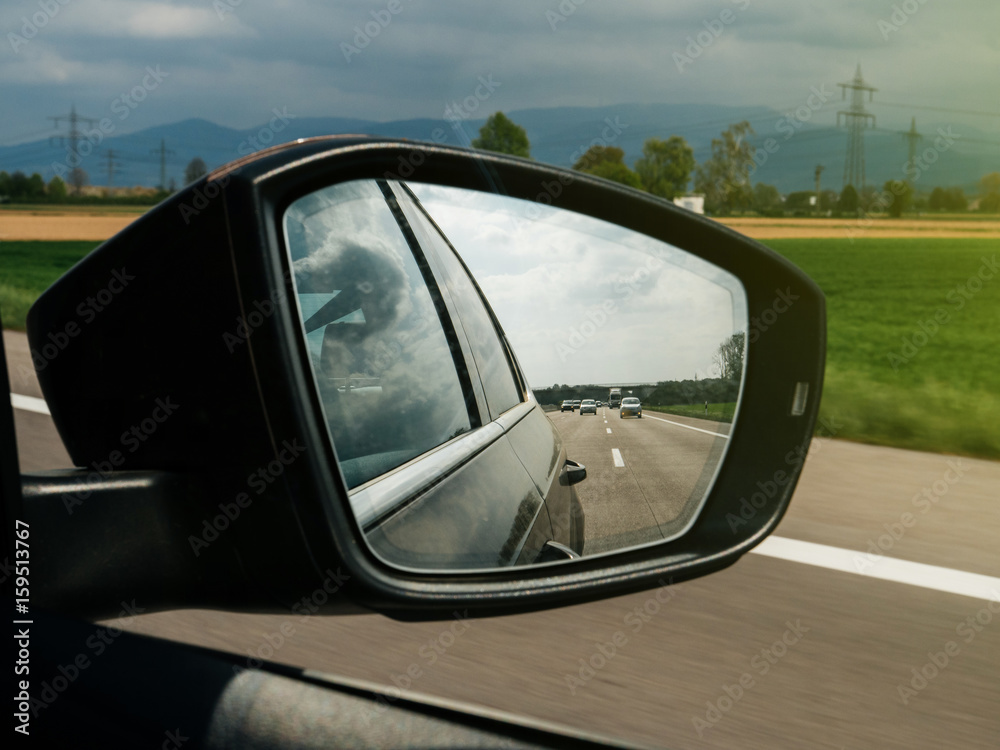 Rear mirror view with typical German landscape - mountains, good autobahn and marked lanes highway 