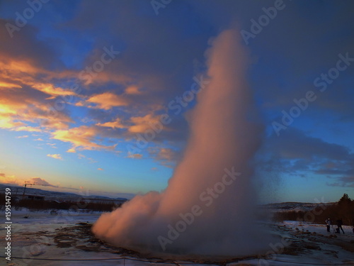 Shot of the ejection of the geyser Strokkur in Iceland during winter with a sunrise in the background.