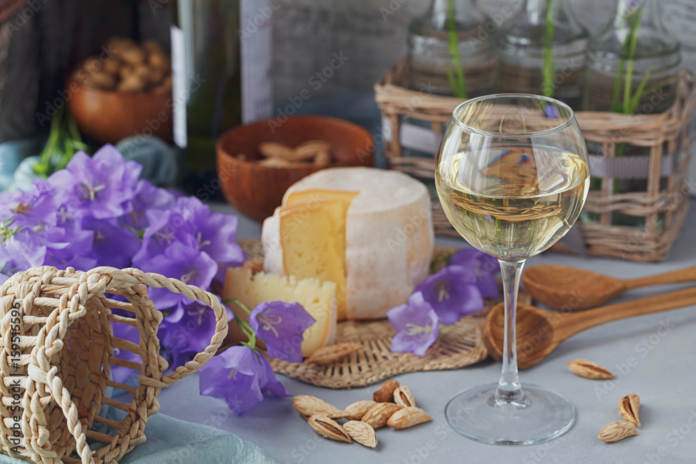 A head of fresh organic cheese served with bread, nuts, white wine and summer flowers.