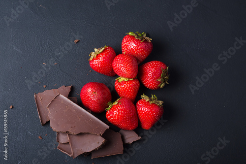 Strawberry with slices of chocolate on a dark background