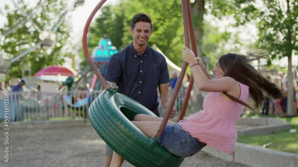 Medium shot of man spinning woman on tire swing at amusement park. Pleasant Grove, Utah, United States Medium shot of man spinning woman on tire swing at amusement park. Pleasant Grove, Utah, United States