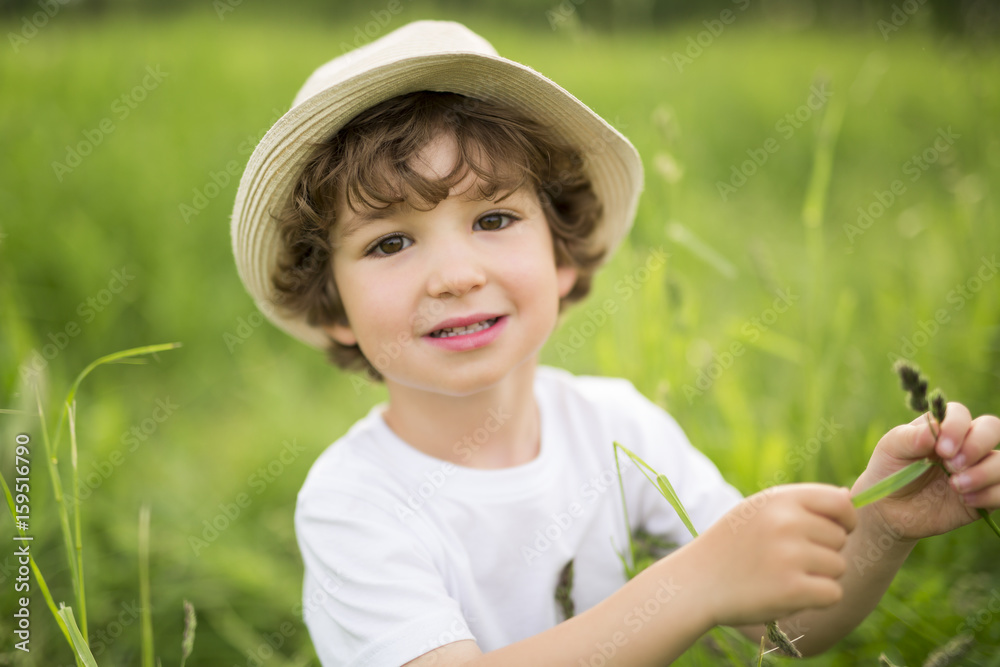 Portrait of adorable kid boy with hat standing on a summer meadow Portrait of adorable kid boy with hat standing on a summer meadow