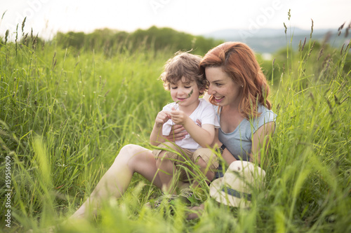 Cute kid boy with his mother on a summer meadow