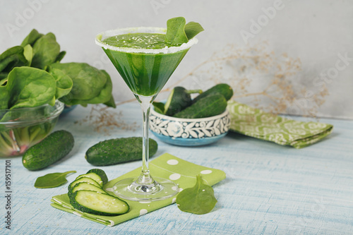 Green spinach and cucumber smoothie on light blue wooden background. photo