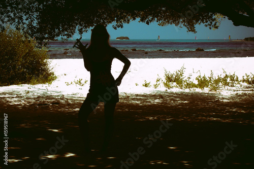 Silhouette of a girl in a short dress and with a cigar at the ocean s shore  