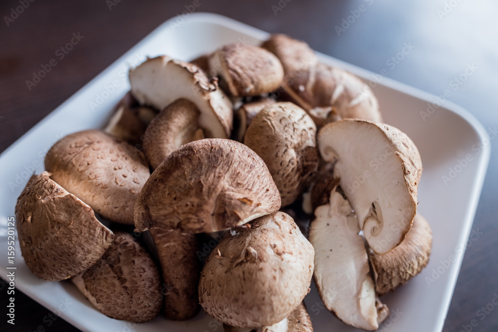 Cutting shiitake mushroom for cooking on with dish on dark background