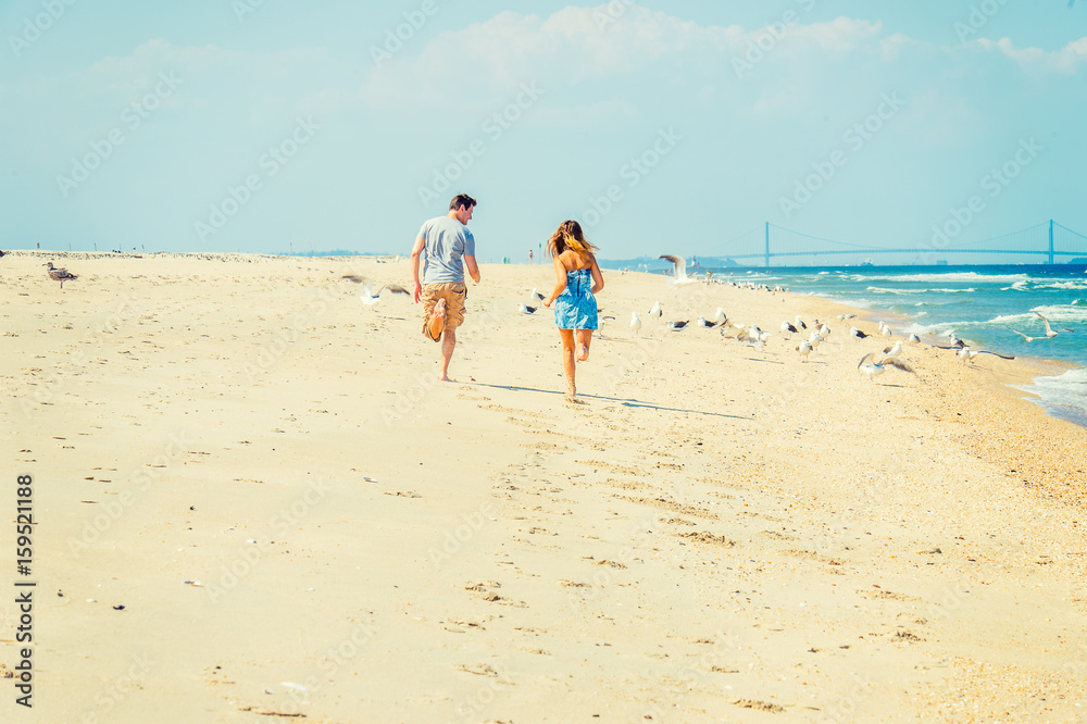 Young American Couple running, relaxing on the beach in New Jersey, USA Young American Couple running, relaxing on the beach in New Jersey, USA