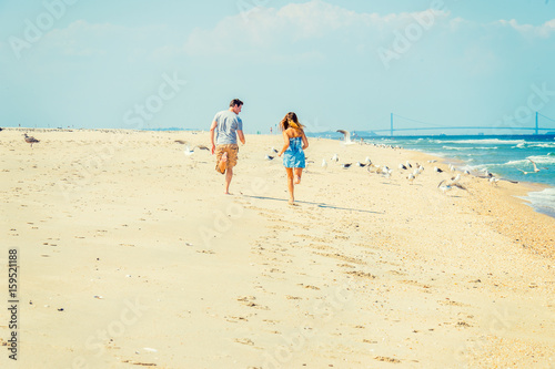 Young American Couple running, relaxing on the beach in New Jersey, USA