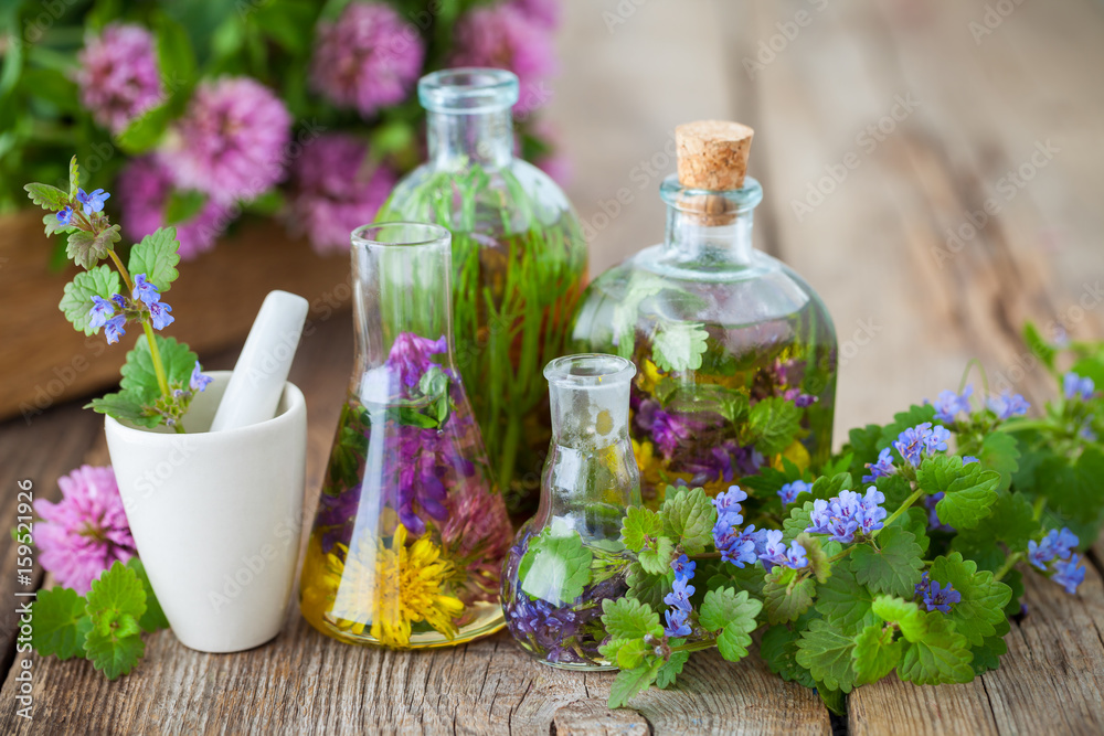 Bottles of tincture or infusion of healthy herbs, mortar and healing plants on old wooden board. Herbal medicine. Bottles of tincture or infusion of healthy herbs, mortar and healing plants on old wooden board. Herbal medicine.