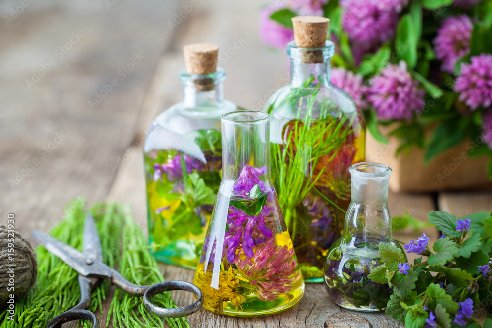 Bottles of tincture or infusion of healing herbs, scissors, medicinal herbs on wooden board. Herbal medicine concept. Bottles of tincture or infusion of healing herbs, scissors, medicinal herbs on wooden board. Herbal medicine concept.