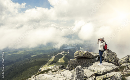 Woman photographer taking photo at mountain peak.