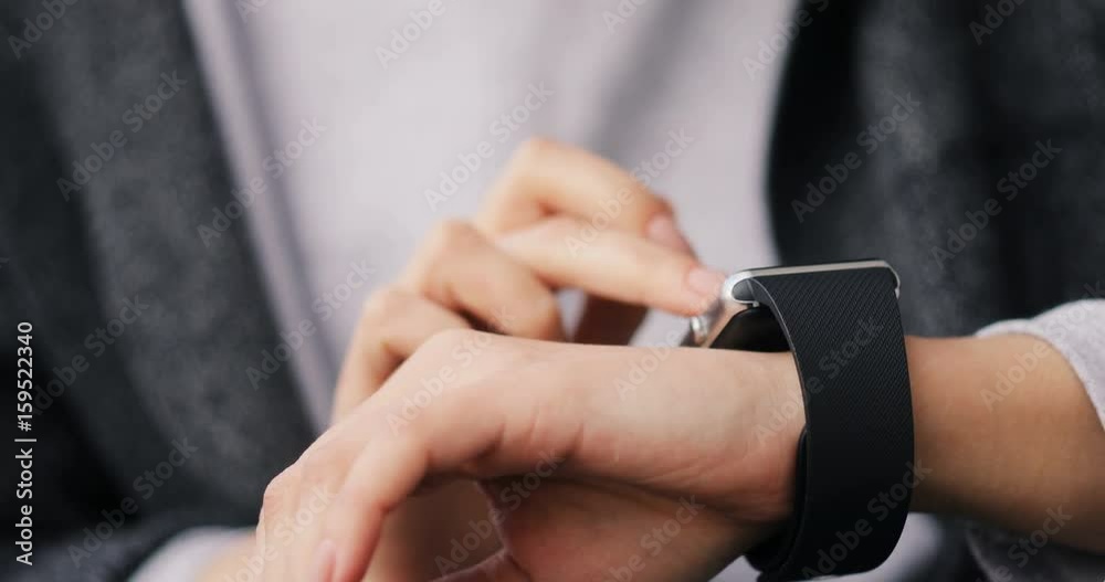 Young woman making gestures on her wearable smartwatch computer device, smart watch close up hands 4k