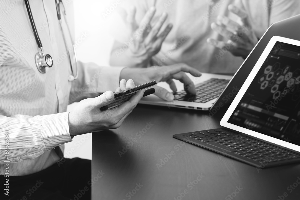 Medical co working concept,Doctor working with smart phone and digital tablet and laptop computer to meeting his team in modern office at hospital,black and white