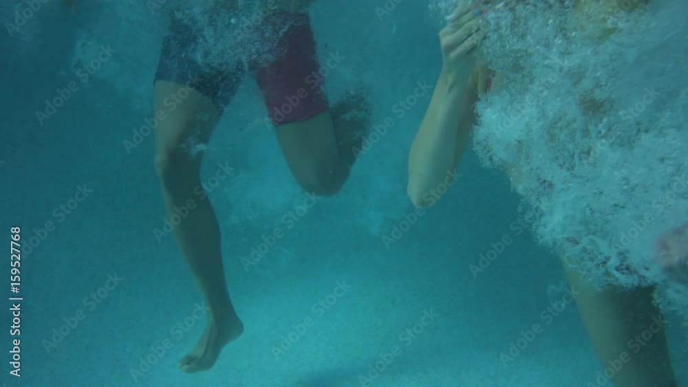 Medium slow motion tracking shot of friends jumping into pool. Cedar Hills, Utah, United States