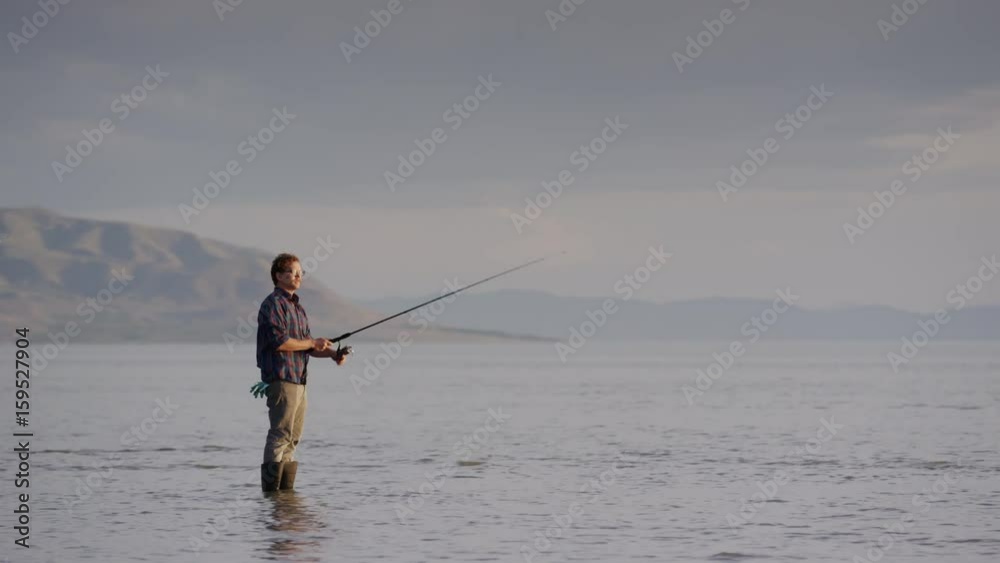 Wide panning shot of man watching fly fishing at lake. Vineyard, Utah, United States Wide panning shot of man watching fly fishing at lake. Vineyard, Utah, United States