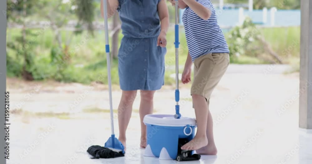 Happy asian family cleans the room. Mother and son do the cleaning in the house. A young woman and a little child boy wiped the dust and vacuumed the floor. Happy asian family cleans the room. Mother and son do the cleaning in the house. A young woman and a little child boy wiped the dust and vacuumed the floor.
