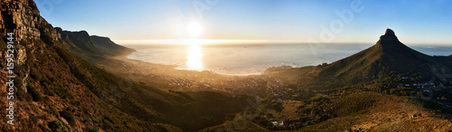 Wide high resolution landscape image taken in cape town, south africa during golden hour just before sunset, with a view of the ocean, city and surrounding mountains. photo